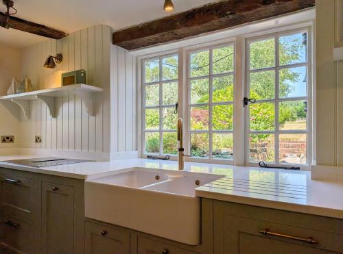 a kitchen with a large sink and two windows at Brooks Farmhouse - Pulborough in Pulborough