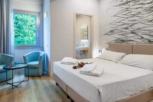 a bedroom with a large bed and a blue chair at Hotel De La Ville depandance di Hotel Augustus in Fano