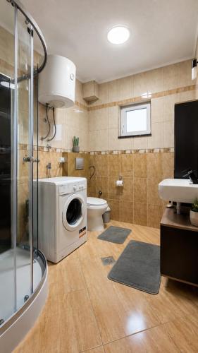 a bathroom with a washing machine and a toilet at Apartman Promaja in Široki Brijeg
