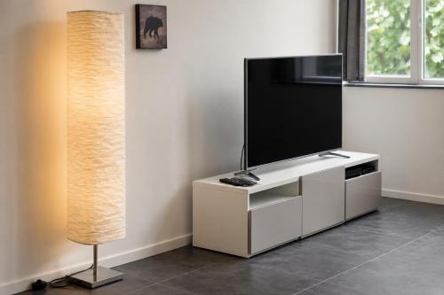 a living room with a television and a lamp at Apart'Hotel Liège City Centre in Liège