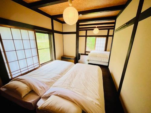 a bedroom with two beds in a room with windows at Matsunokitei Chalet Irori in Otari