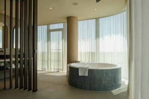 a bath tub in a bathroom with large windows at Van der Valk Hotel Woerden in Woerden