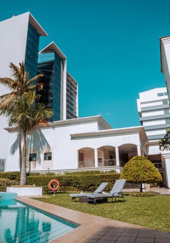 a building with two lounge chairs next to a swimming pool at Hotel Vip Grand Maputo in Maputo