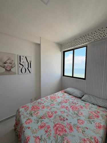 a bedroom with a bed with a floral bedspread and a window at Summer house in Olinda