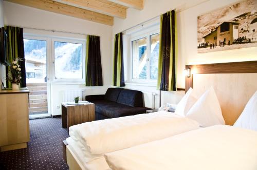 Habitación de hotel con 2 camas y sofá en Hotel Tannenhof, en Ischgl