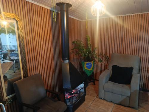 a living room with two chairs and a wood stove at Hotel Central in Arroio do Meio