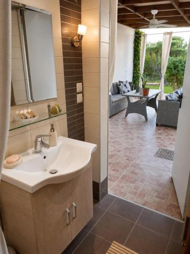 a bathroom with a sink and a living room at The Secret Garden Peraia in Perea