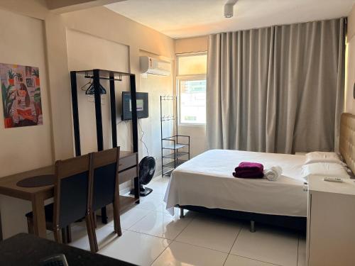 a bedroom with a bed and a table and a desk at Stúdio Beira Mar in Fortaleza