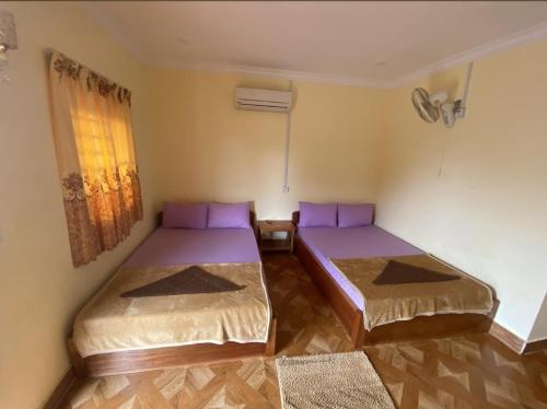 two beds in a room with purple pillows at Senmonorom in Senmonorom