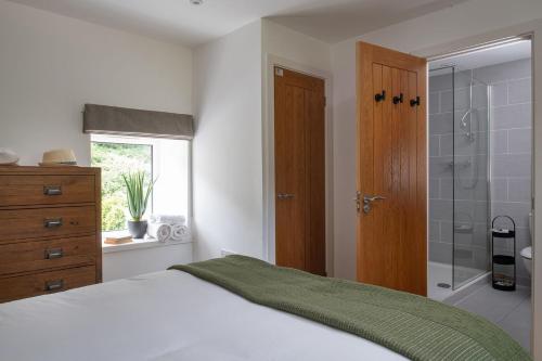 a bedroom with a bed and a glass shower at Bayholme House in Oxwich