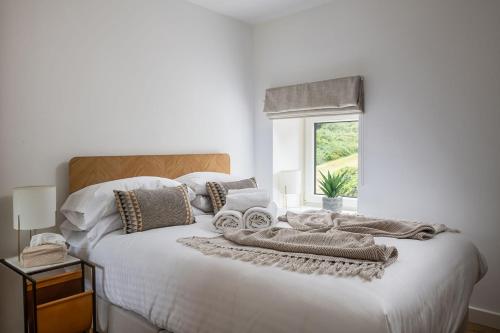 a bedroom with a white bed with towels on it at Bayholme House in Oxwich