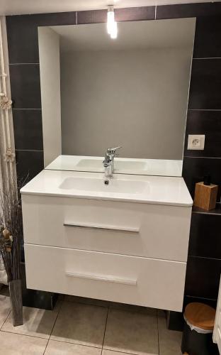 a white sink in a bathroom with black tiles at Le Bellevue in Xonrupt-Longemer