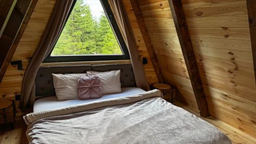 a small bed in a room with a window at Horizons by PeaksView Chalets in Žabljak