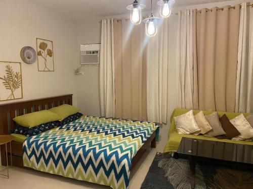 a bedroom with a bed and a couch at spacious condo unit 1P olvera residences in Bacolod