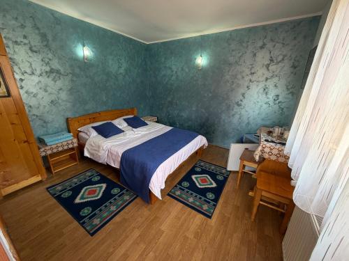 a bedroom with a bed with blue walls and wooden floors at Casa Lav in Sinaia
