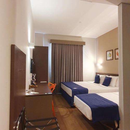 a hotel room with two beds and a desk at Summit Suítes Hotel Pindamonhangaba in Pindamonhangaba