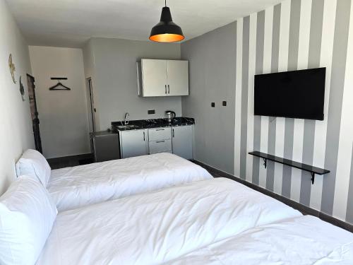two beds in a room with a kitchen and a tv at Chambre d'hôte plage Dalia in Dalia