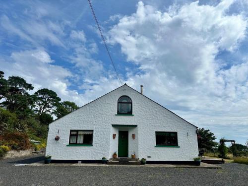 a small white building with a green door at Rainbow Cottage Glenmore in Dundalk