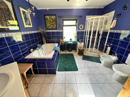 a bathroom with blue tiled walls and a tub and sink at Rainbow Cottage Glenmore in Dundalk