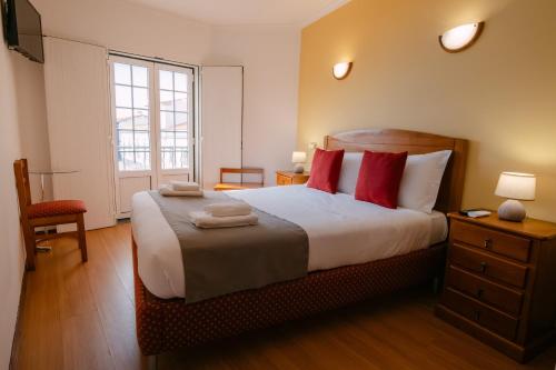 a bedroom with a large bed with red pillows at Hospedaria Canto do Rossio in Vidigueira