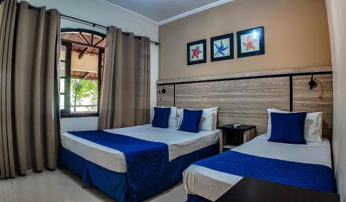 a bedroom with two beds with blue and white sheets at Summit Beach Hotel Boiçucanga in Boicucanga
