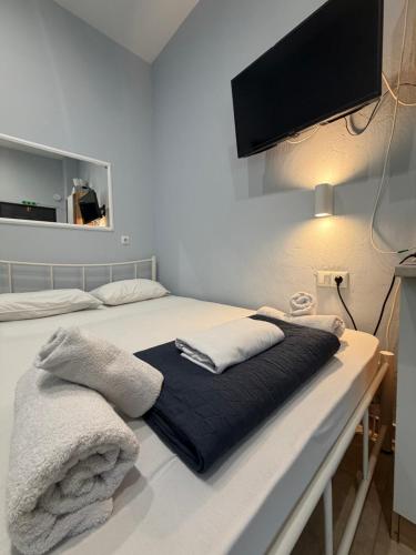 a bed with two pillows and a tv on the wall at Athanias Studio in Drama