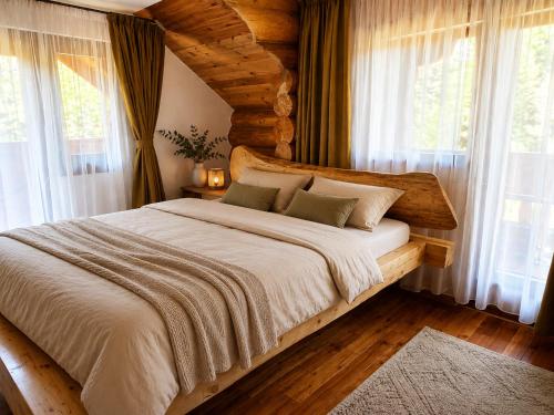 a bedroom with a large bed with windows at Cabana Perla Muncelului in Stulpicani
