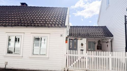 a white house with a white fence in front of it at Charming and historic house in Flekkefjord