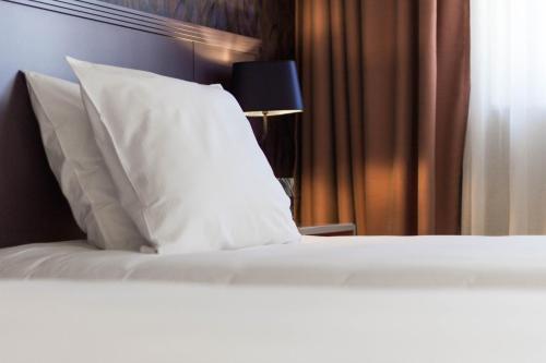 a bed with white sheets and pillows in a room at Hôtel Oceania Le Métropole in Montpellier
