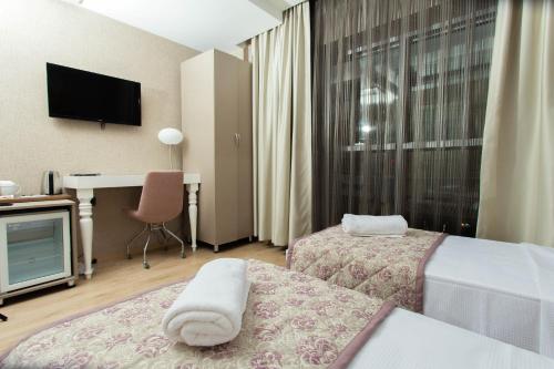 a hotel room with two beds and a desk at Hotel Iz in Izmir