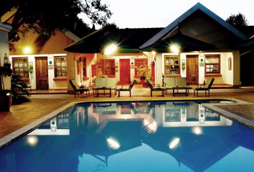 una piscina davanti a una casa di notte di Waterkloof Guest House a Pretoria