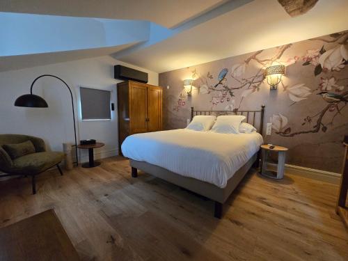a bedroom with a large bed and a chair at Hôtel Le Groom in Laprade
