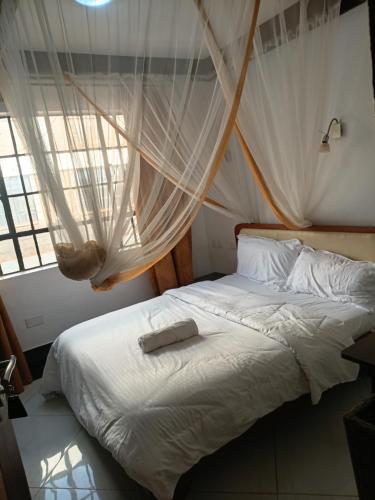 a bedroom with a white bed with a net at The Sychar Palace Hotel in Kanga