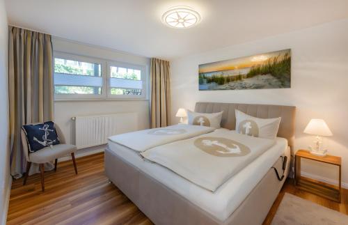 a bedroom with a large white bed and a chair at Krauses Unterdeck in Loddin