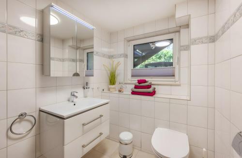 a white bathroom with a sink and a window at Krauses Unterdeck in Loddin