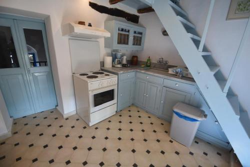 a kitchen with a white stove top oven next to a staircase at Avgonima Sunset Medvial Suite in Chios