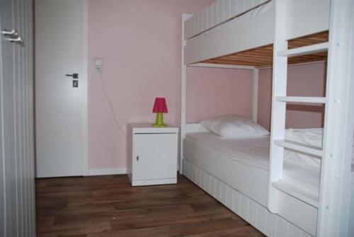 een slaapkamer met een wit stapelbed en een rode lamp bij Les Haies in Solwaster