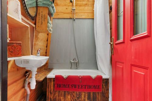 a bathroom with a tub and a sink and a red door at Roulotte Champêtre Bella in Brix