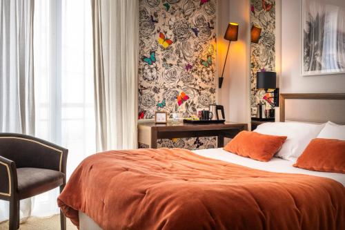 a bedroom with a bed with an orange blanket and a chair at Hotel & Spa Les Roches Noires in Les Sables-d'Olonne