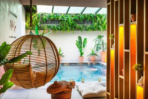 a room with a swimming pool with a large rattan swing at Hotel & Spa Les Roches Noires in Les Sables-d'Olonne