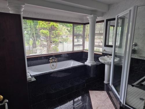 a bathroom with a bath tub and a sink at Driftwood on 10 La Lucia in Durban