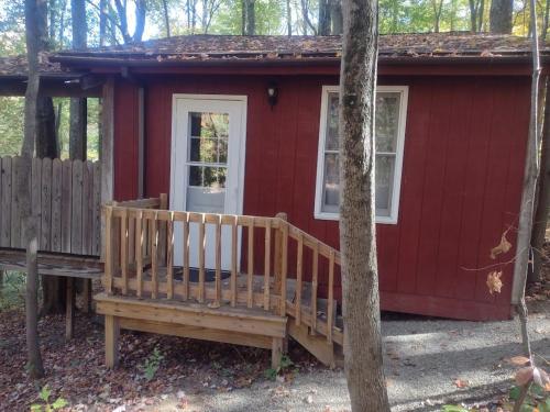 a red tiny house in the woods with a porch at Thunder Ridge Cabins B&B - Otter Lodge in Rockbridge