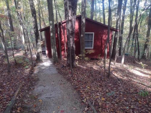 a small red house in the woods with a trail at Thunder Ridge Cabins B&B - Otter Lodge in Rockbridge