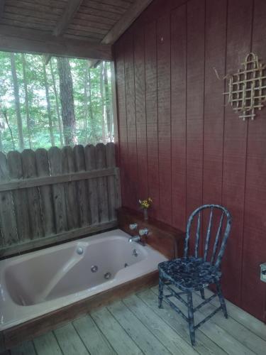 a bath tub sitting in a room with a chair at Thunder Ridge Cabins B&B - Wolf Den in Rockbridge