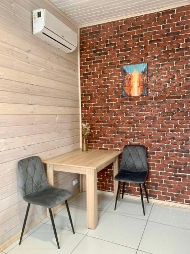 a wooden table and two chairs next to a brick wall at Еко апартаменти DOM Art in Ovruch