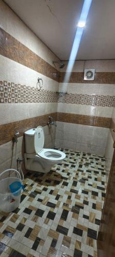 a bathroom with a toilet and a tiled floor at COCHIN CINEMA Rooms in Cochin