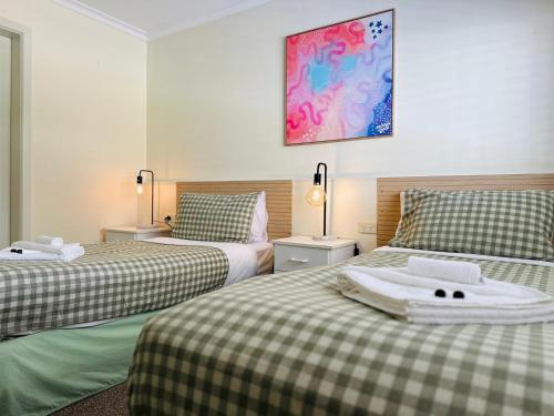 a bedroom with two beds with green and white sheets at Stonez Boutique Accommodation in Clunes