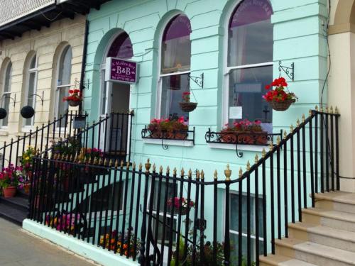 a blue building with flower boxes on the windows at A Maiden Rest in Weymouth