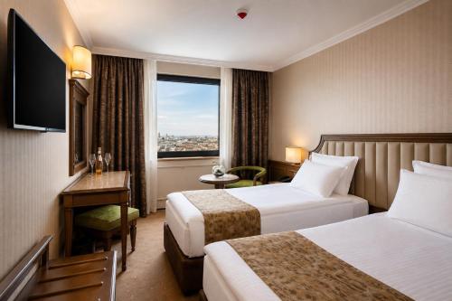 a hotel room with two beds and a window at Astoria Grand Hotel in Sofia