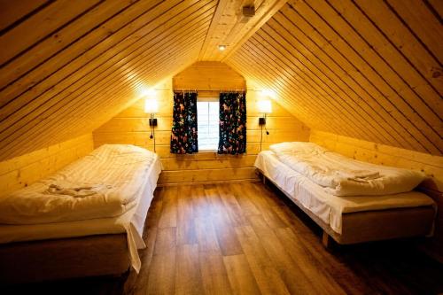 two beds in a wooden room with a window at Värdshuset Flottaren in Vansbro
